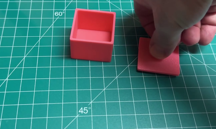 The printed box and lid on a cutting mat, with the lid being lifted away