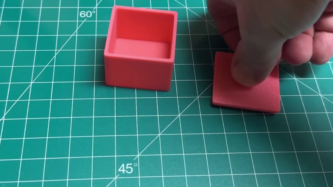 A printed pink box and its separate lid on a cutting mat, made with boolean operations in Bambu Studio