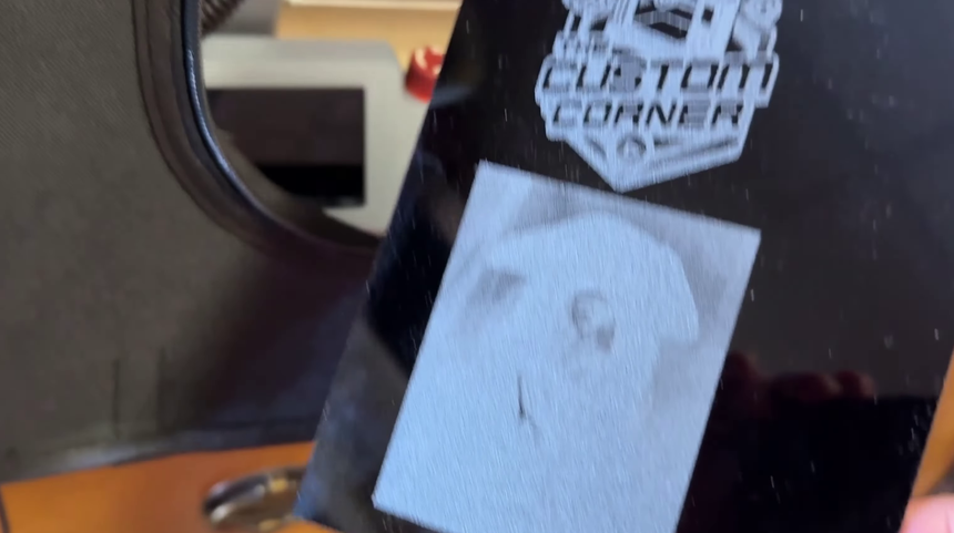 A black acrylic sheet with a crisp engraved logo above and a failed detailed image below that reads as a frosted gray block
