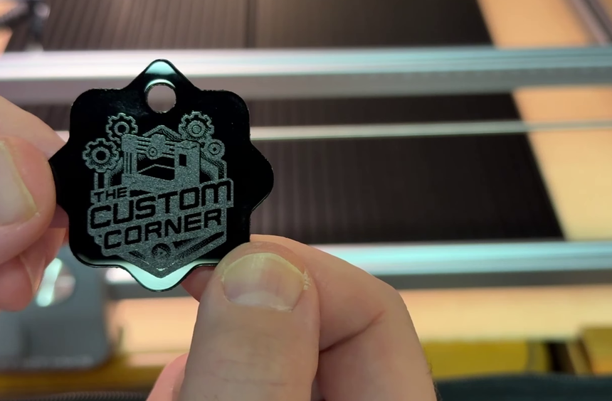 A finished black acrylic keychain with an engraved logo and cleanly cut edges