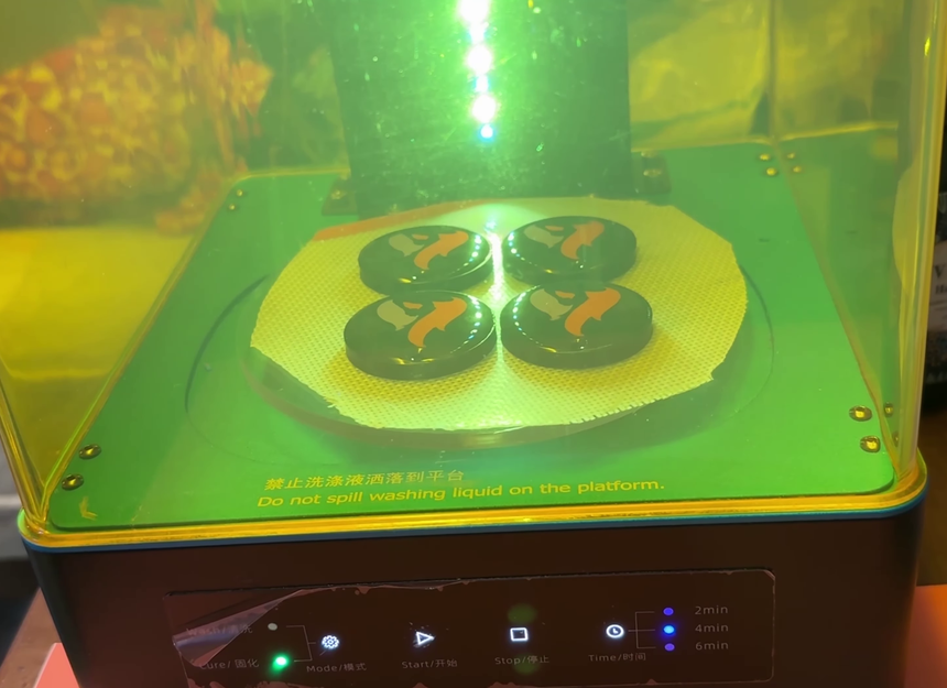 Four resin filled keychains on the silicone mat inside the curing station under UV light, with the timer offering 2, 4 and 6 minutes