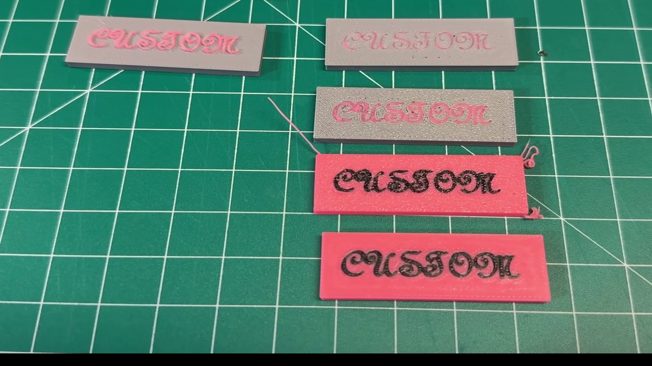 Four printed test plates with the word CUSTOM in a script font, two pale and blurry, two pink and sharp